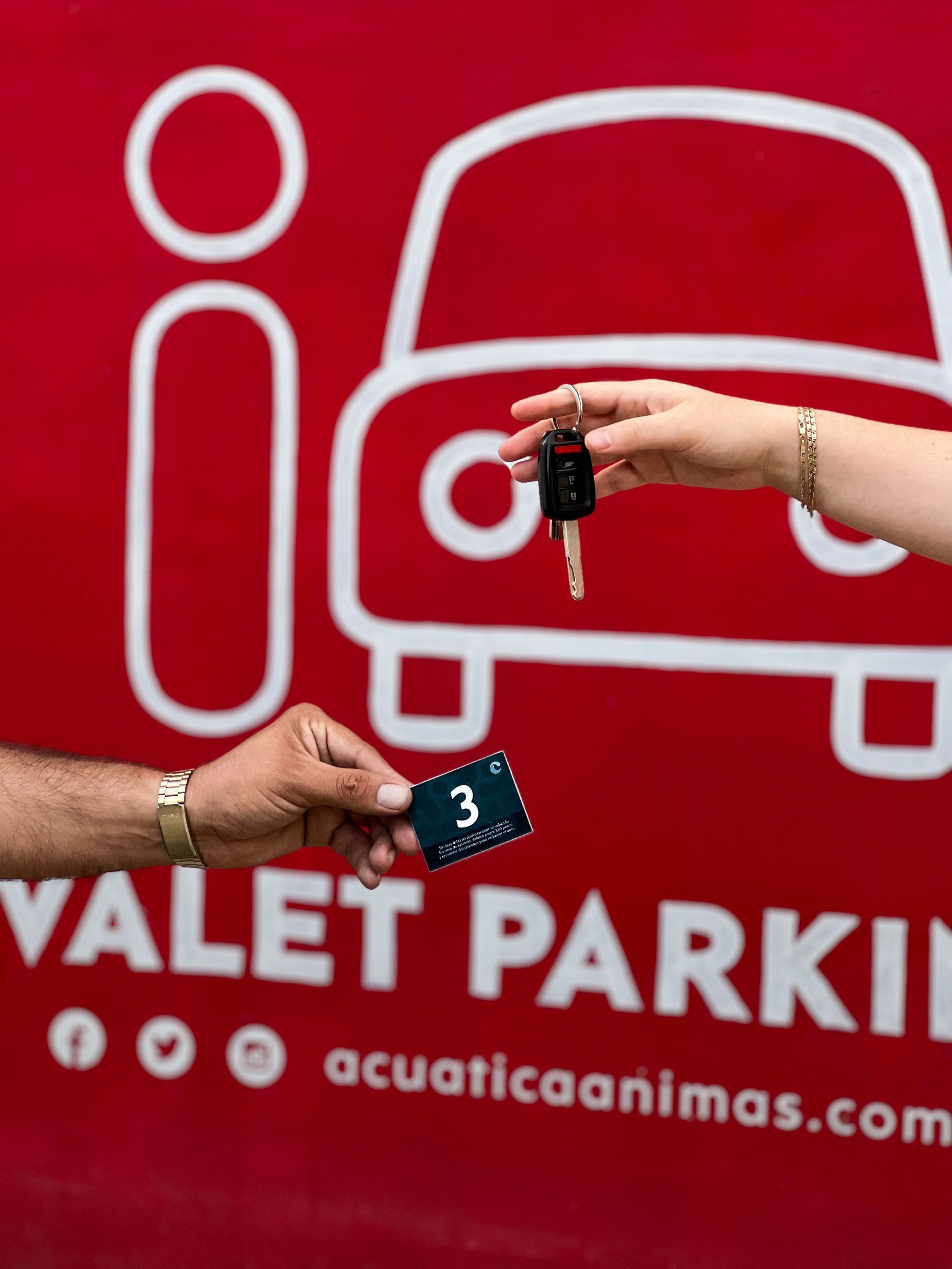 Entregar las llaves del servicio de aparcacoches junto a un cartel rojo de aparcacoches con el icono de un coche.