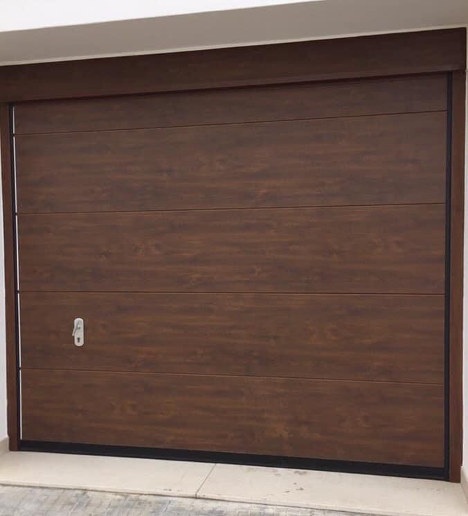 Porta da garage marrone effetto legno, con pannelli orizzontali e maniglia argentata.