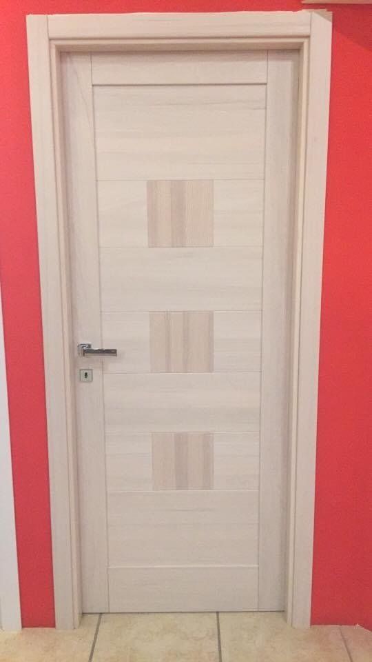Porta interna in legno chiaro con tre pannelli rettangolari verticali;