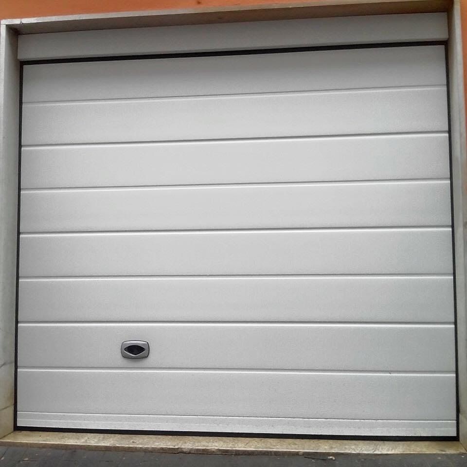 Porta da garage bianca con listelli orizzontali e maniglia, inserita in una struttura in cemento.