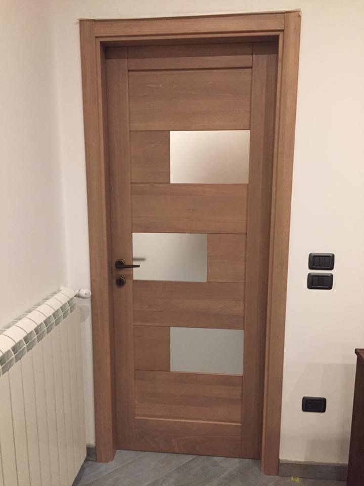 Porta in legno con pannelli in vetro smerigliato, ferramenta nera, inserita in una stanza