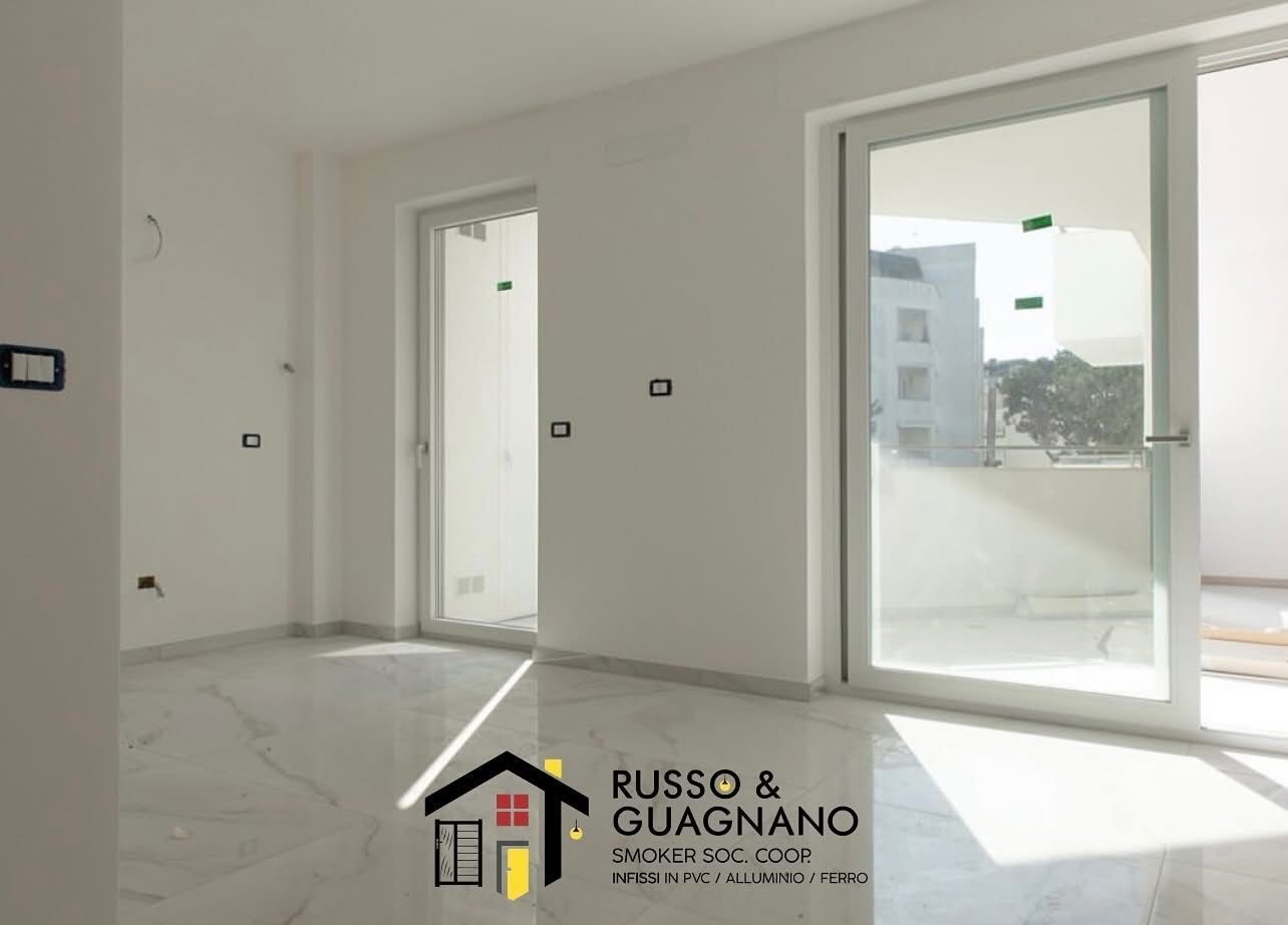 Stanza bianca e vuota con grandi finestre e pavimento in marmo.