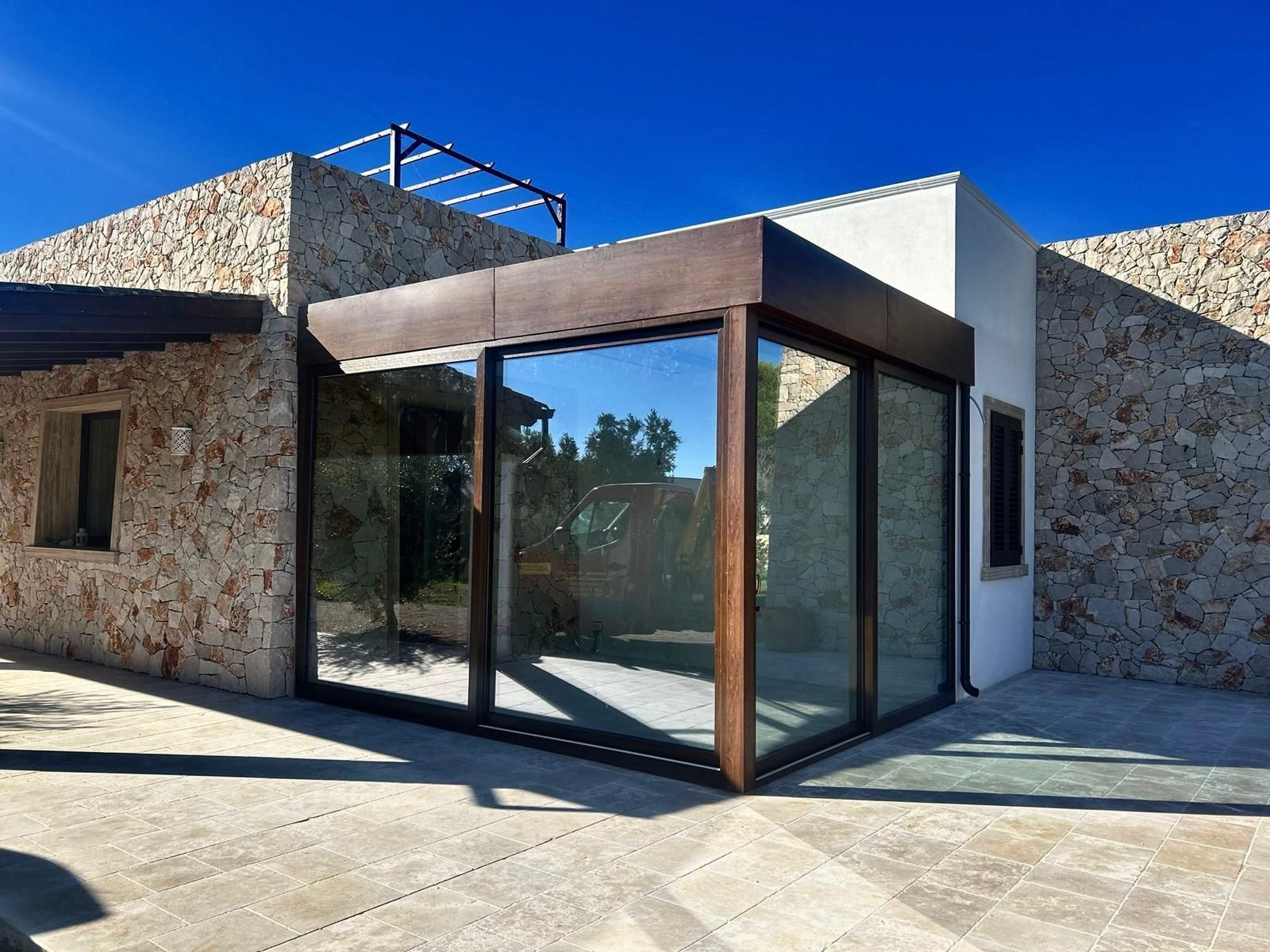 Edificio in pietra con un'ampia vetrata, finiture marroni e cielo azzurro terso.