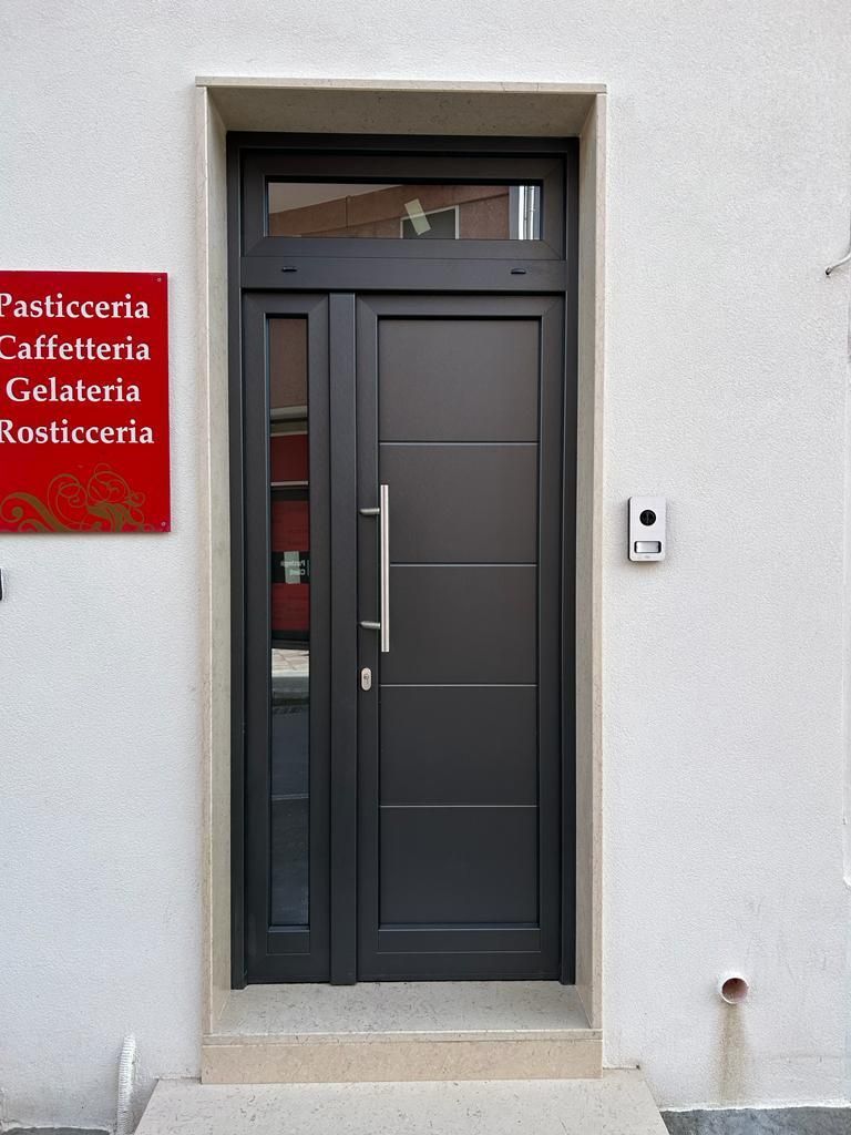 Porta nera con finestra laterale e sopraluce, ingresso di un bar italiano. Insegna con la scritta