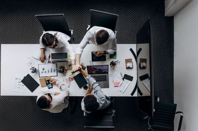 People around a conference table reviewing documents and devices in a meeting room