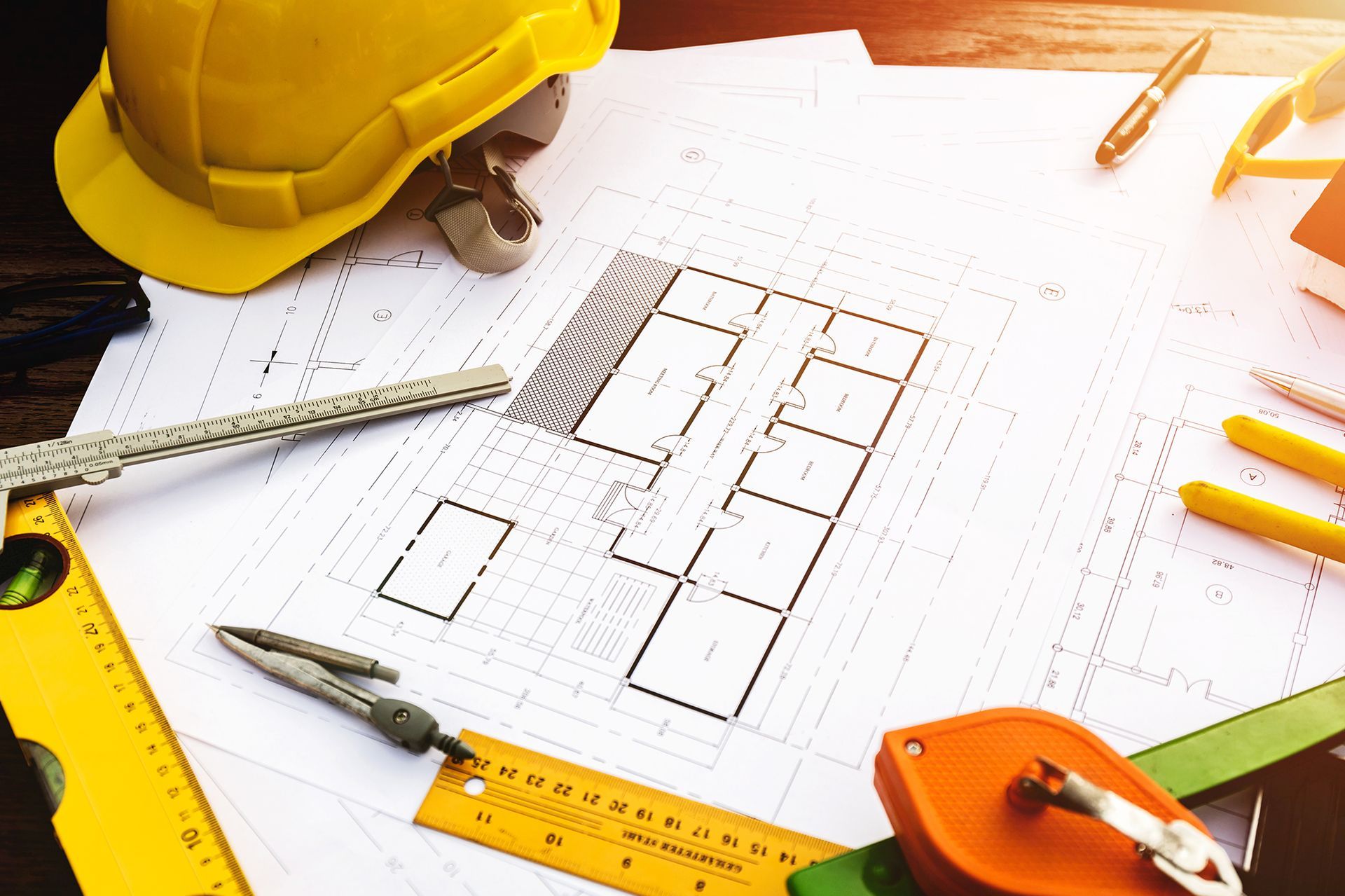 Architectural blueprints with tools like a hard hat, level, and ruler.