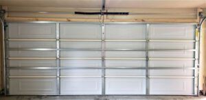 A white garage door is open in a garage.