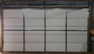 A white garage door is open in a garage.