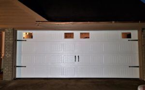 A white garage door with two windows and a brick wall.