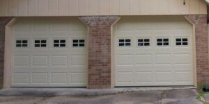 Two white garage doors are sitting next to each other on a brick building.