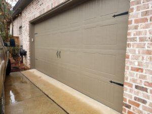 A car is parked in front of a brick garage door.