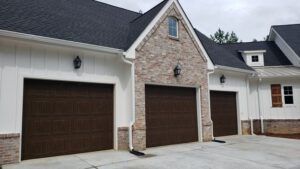There are three garage doors on the side of a house.