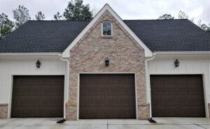 There are three garage doors on the side of a house.