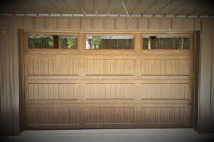 A wooden garage door with three windows in a garage.