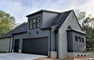 A large gray house with a black garage door and a black roof.