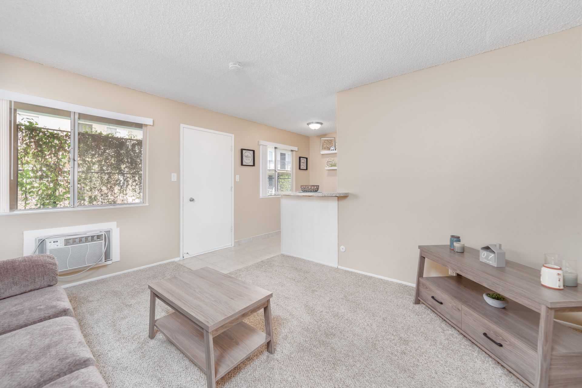 Bright living room with gray sofa, coffee table, window, and kitchen pass-through.