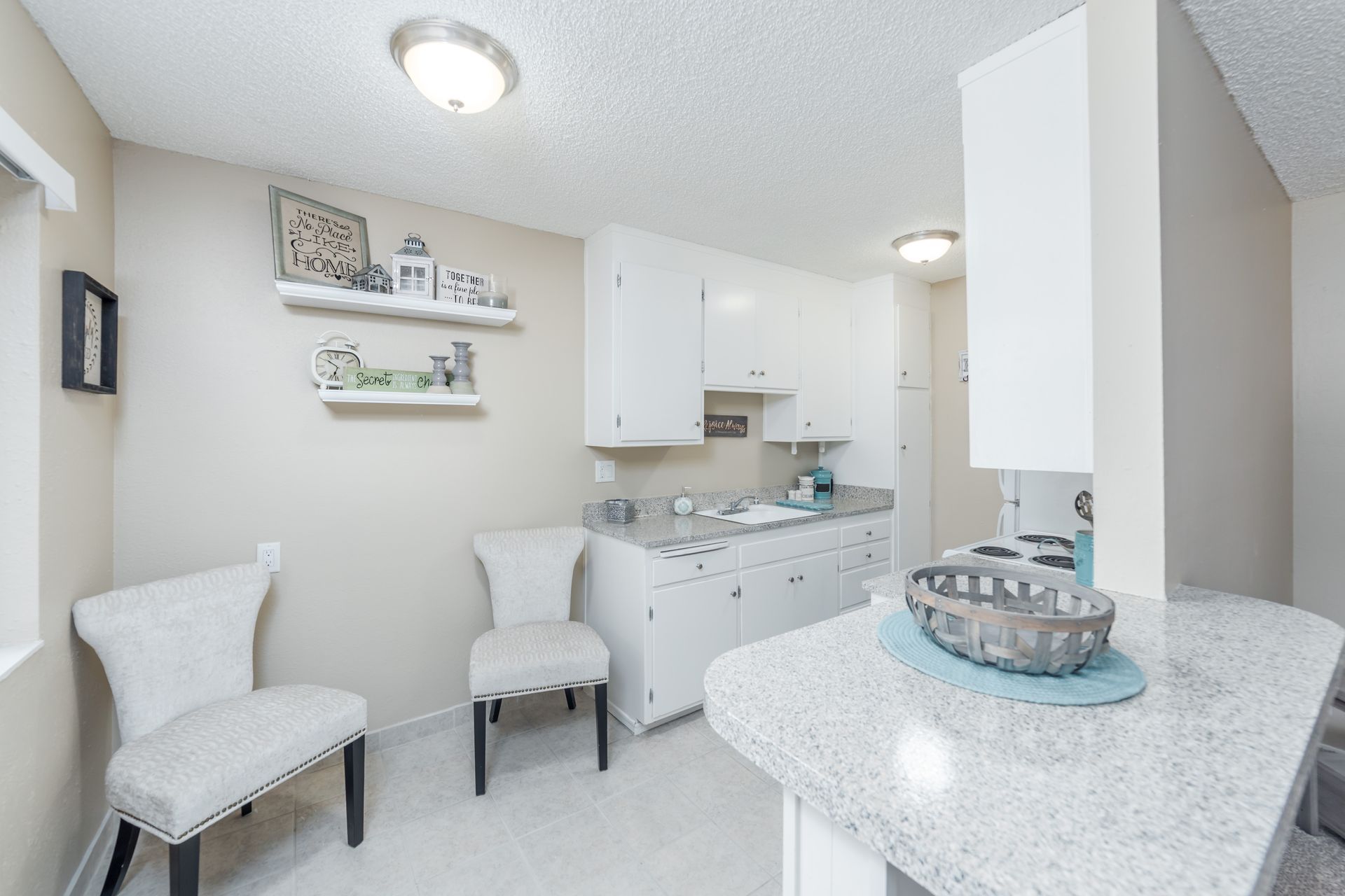 Bright white spa room with chairs, sink, wall shelves, and a countertop display