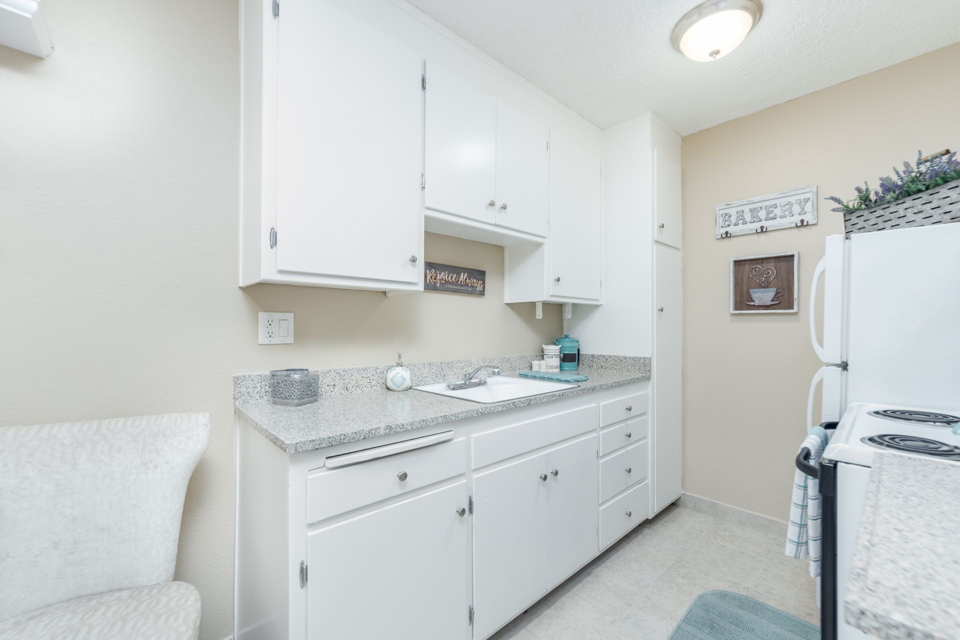 Bright white laundry room with cabinets, granite counter, sink, and washer/dryer area