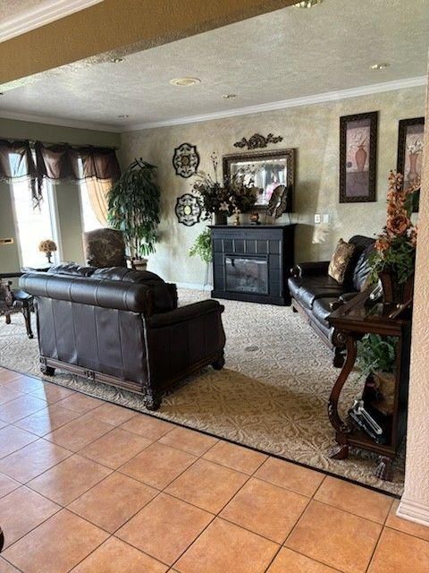 A living room with brown leather couches, a black fireplace, tiled floors, and decorative wall art.