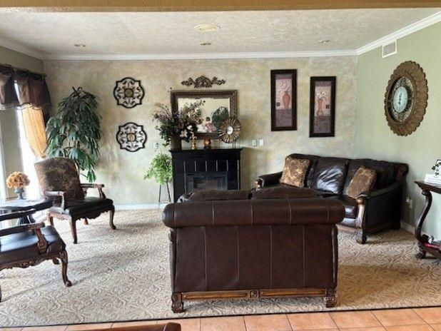 A living room with brown leather sofas and chairs, a fireplace, wall art, and a large decorative mirror on a beige wall.