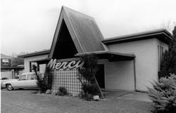 Black and white photo of a 1960s-style Mercury car dealership building featuring a prominent, steep A-frame roof.