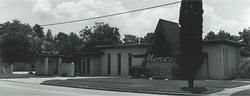A vintage, black-and-white photo of a building with an A-frame entrance and a sign reading 
