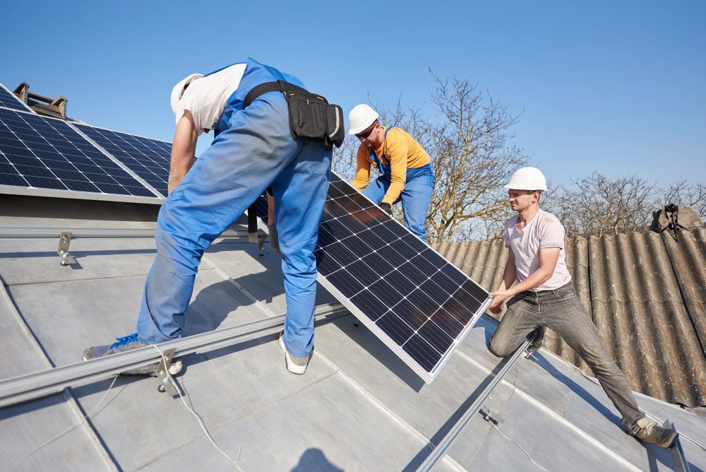 Three Men Are Installing Solar Panels On A Roof — RAFFBRO Electrical Solar & Air Conditioning In Howlong, NSW
