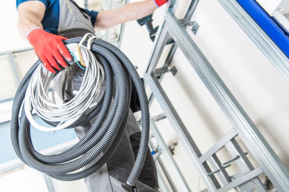 A Man Is Holding A Roll Of Wires In His Hands — RAFFBRO Electrical Solar & Air Conditioning In Beechworth, VIC