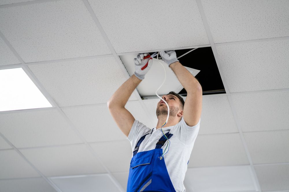 A man is fixing a light fixture on the ceiling.