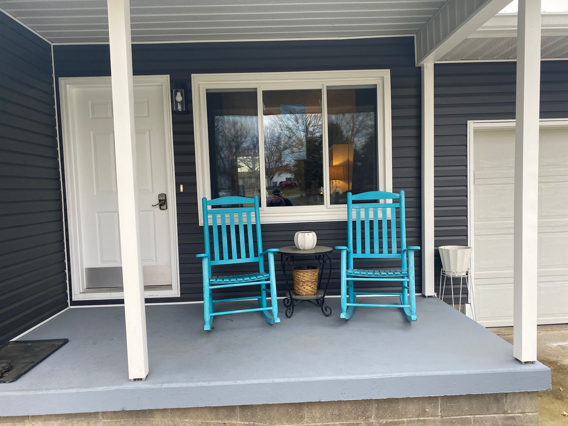 Two blue rocking chairs are on the porch of a house.
