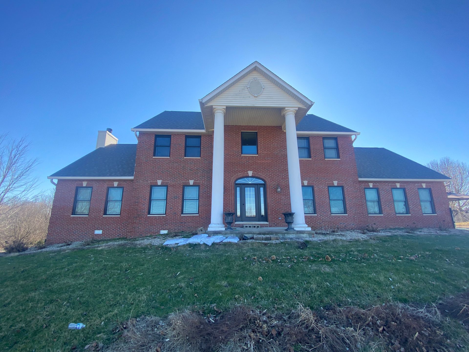 A large brick house with columns and a blue sky in the background