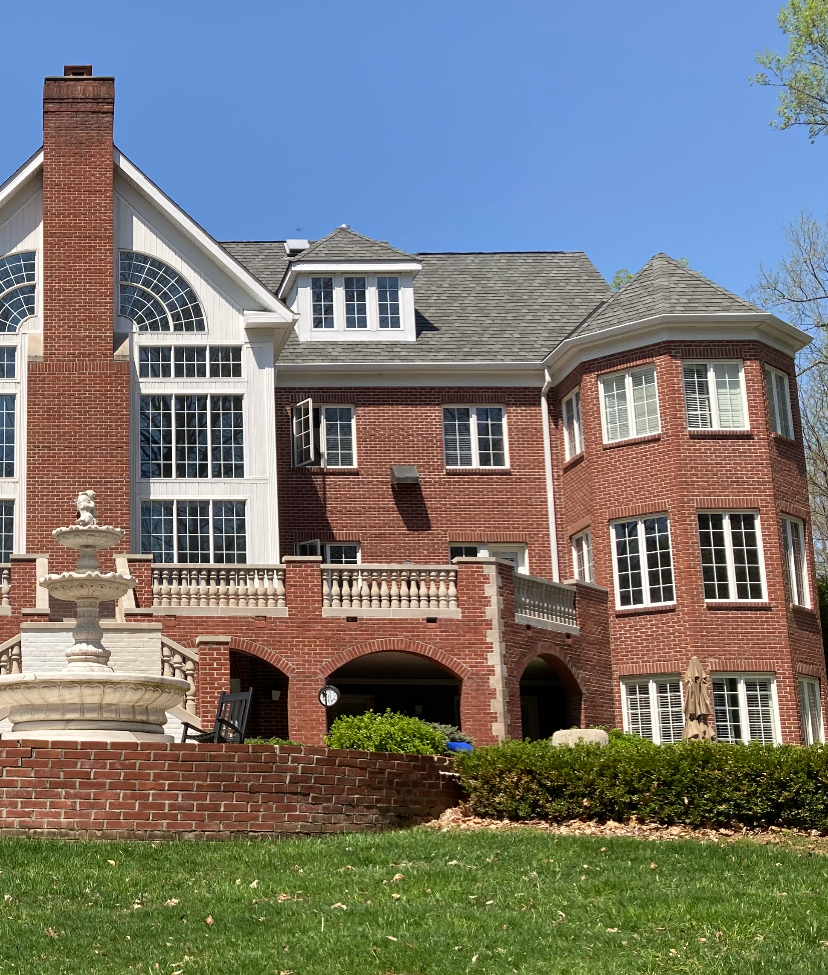 A large brick house with a fountain in front of it