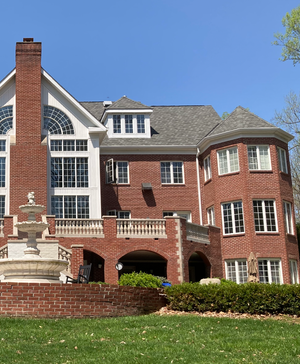 A large brick house with a fountain in front of it
