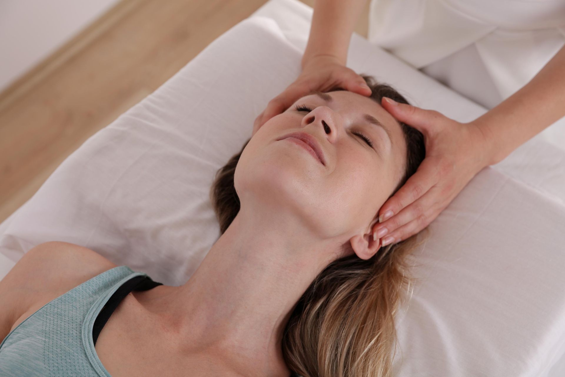Person receiving a facial massage on a treatment table, eyes closed, in a spa setting