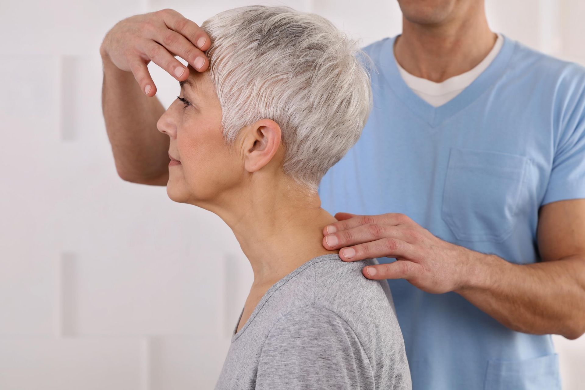 Physical therapist examining a patient’s neck and shoulder in a clinic setting