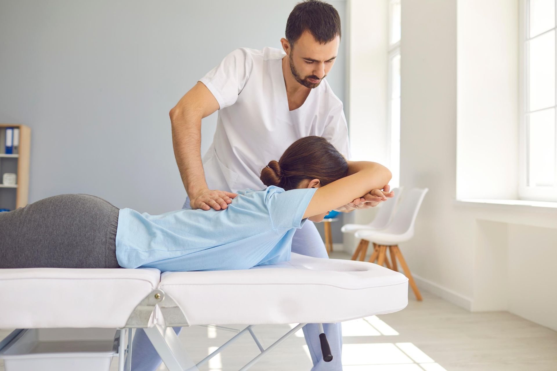 Therapist treating patient on a massage table in a bright clinic room