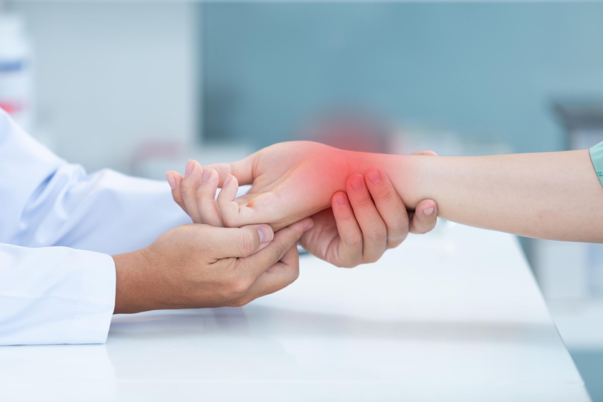 Doctor holding a patient’s wrist in a clinical setting, with a red pain highlight on the forearm