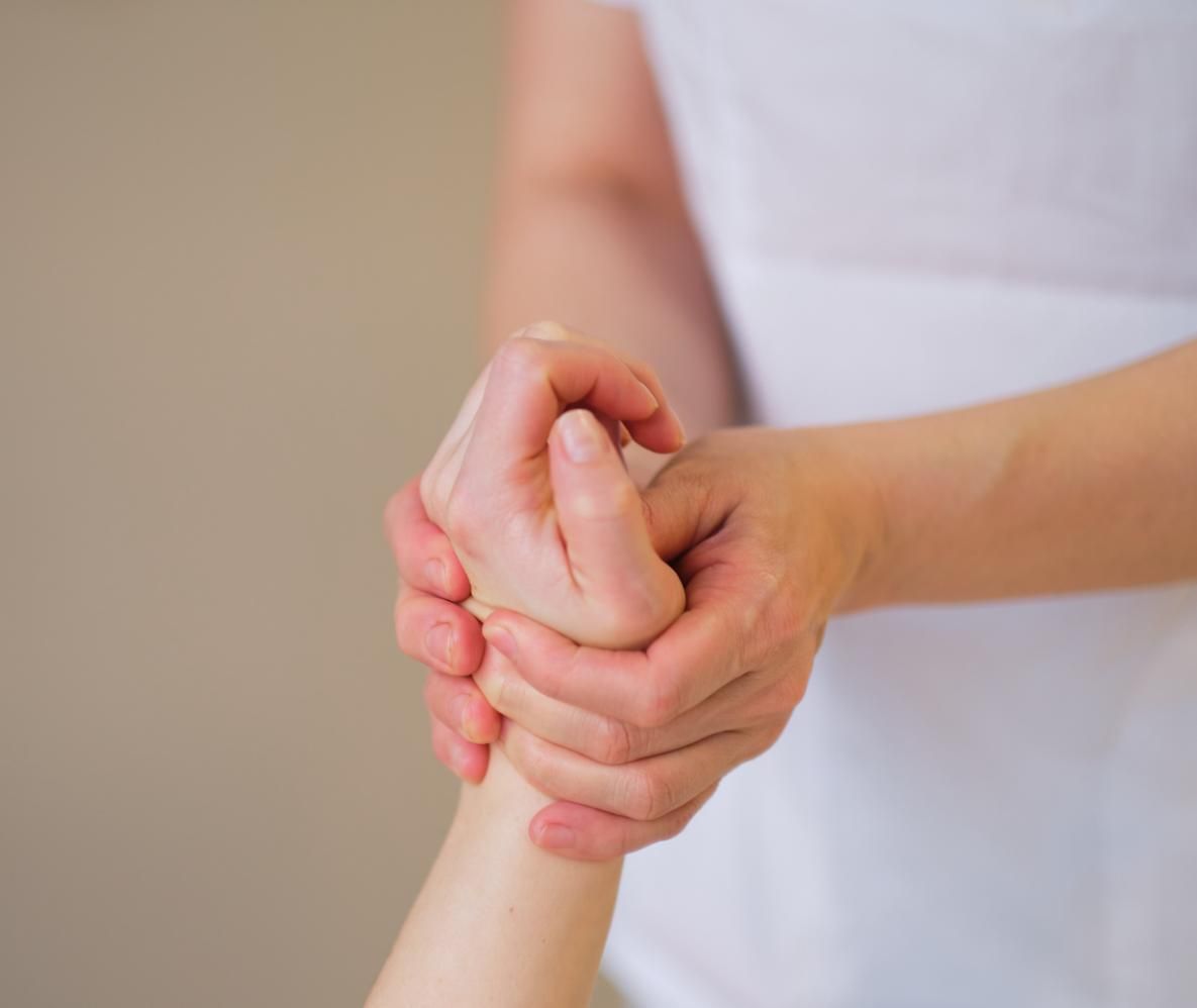 Hands clasped together in a supportive gesture against a plain background