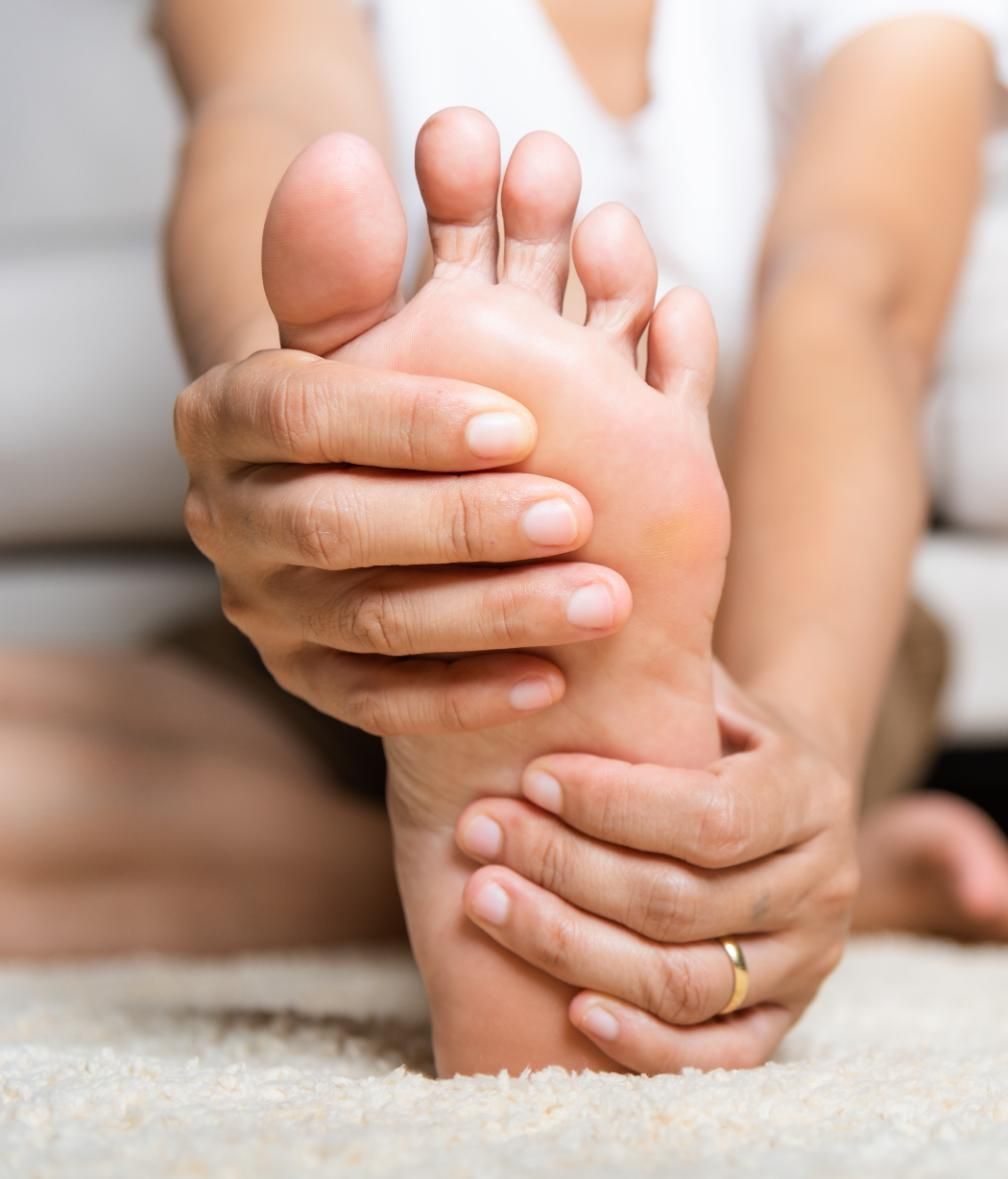 Hands massaging the sole of a bare foot in a close-up spa setting