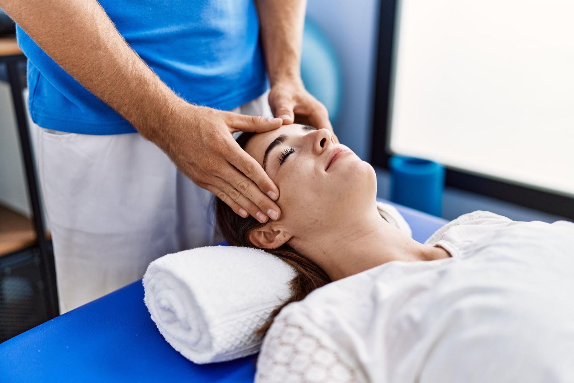 Therapist performing head massage on a patient lying on a treatment table