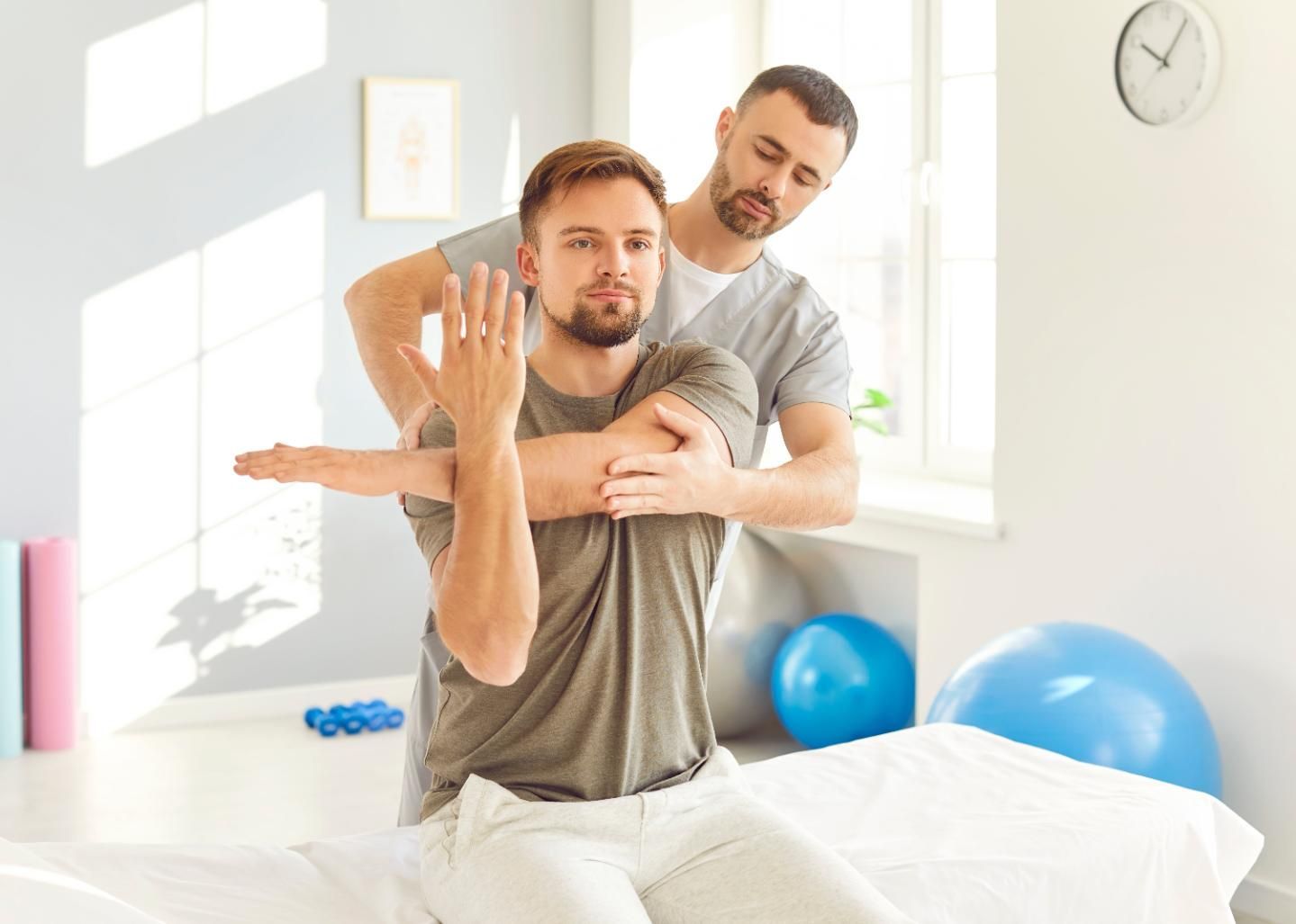 Physical therapist helping a patient stretch on a bed in a bright therapy room
