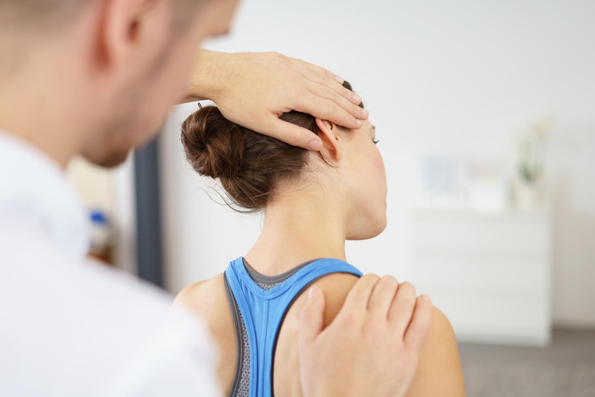 Physical therapist holding a patient’s neck and shoulder during a treatment session