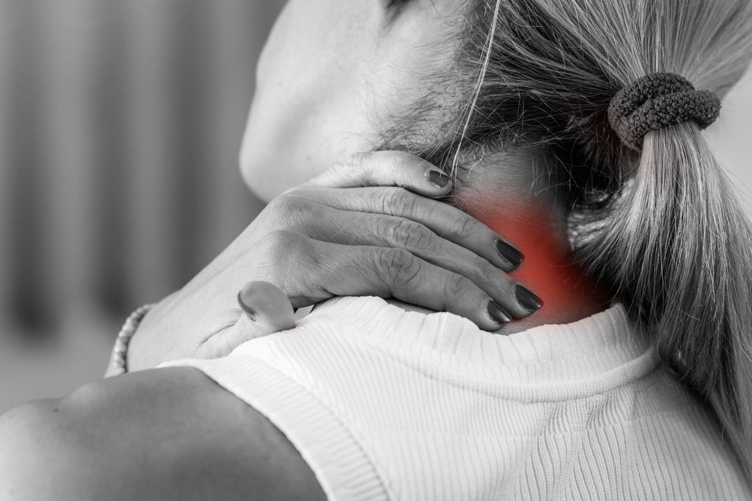Person receiving a shoulder massage from another person in a blue shirt, close-up indoors