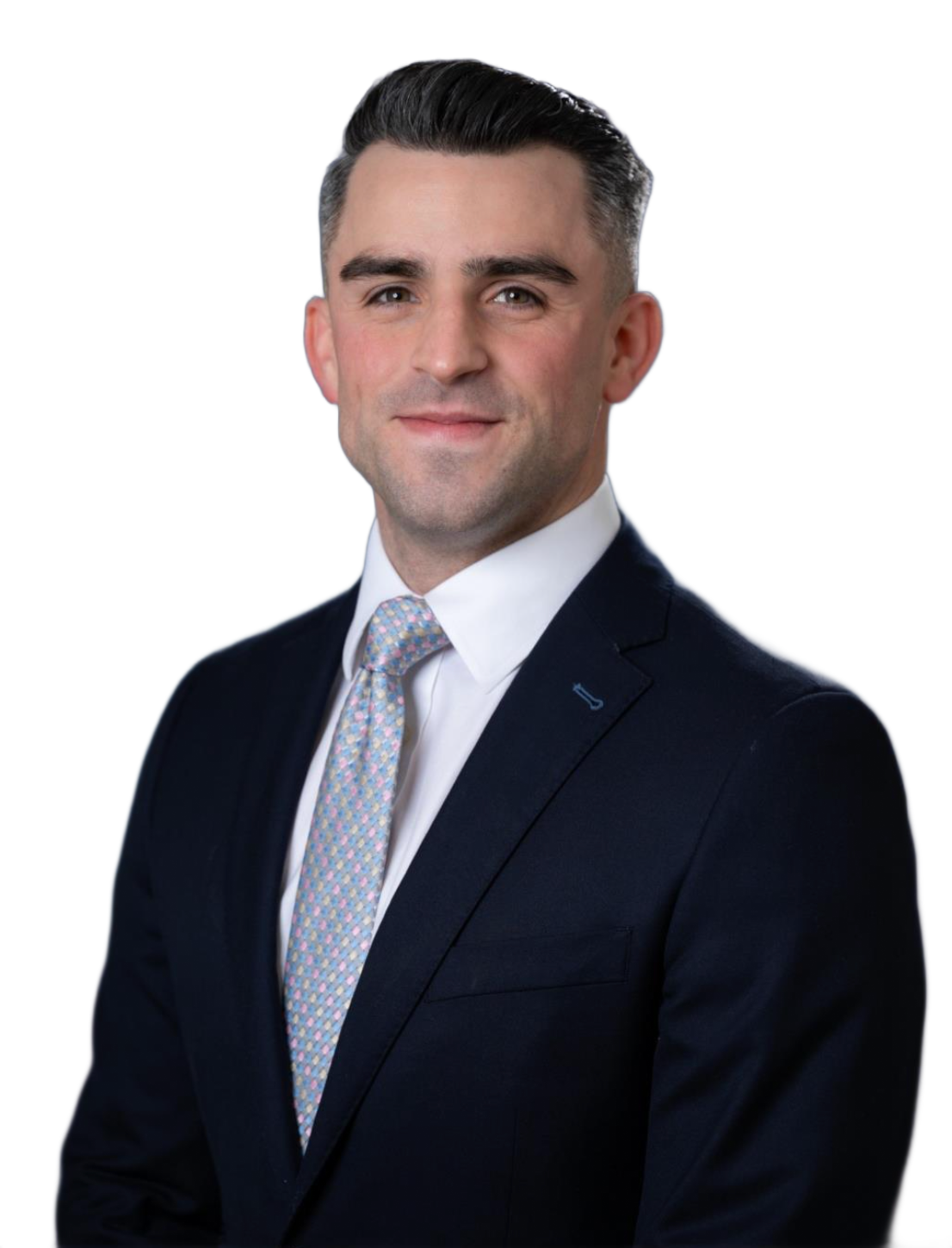 A smiling man in a suit and tie poses for a professional portrait against a blurred background.