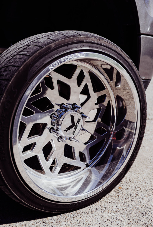 A close up of a car wheel in a parking lot.