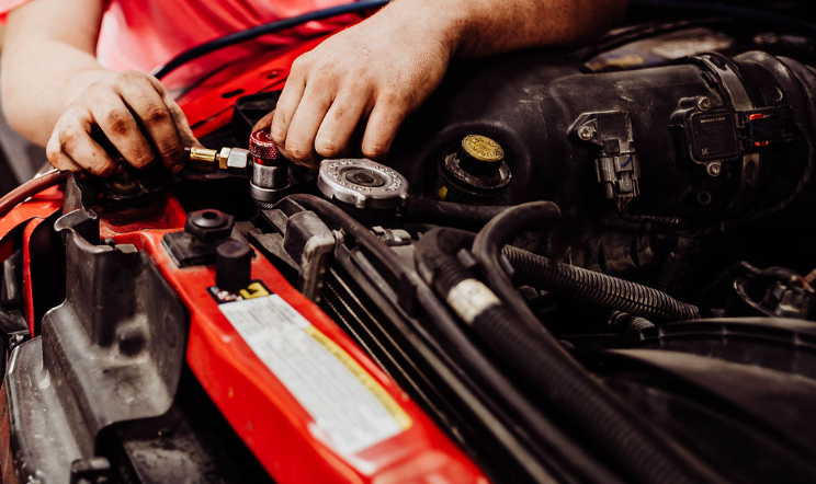 A man is working on the engine of a car.