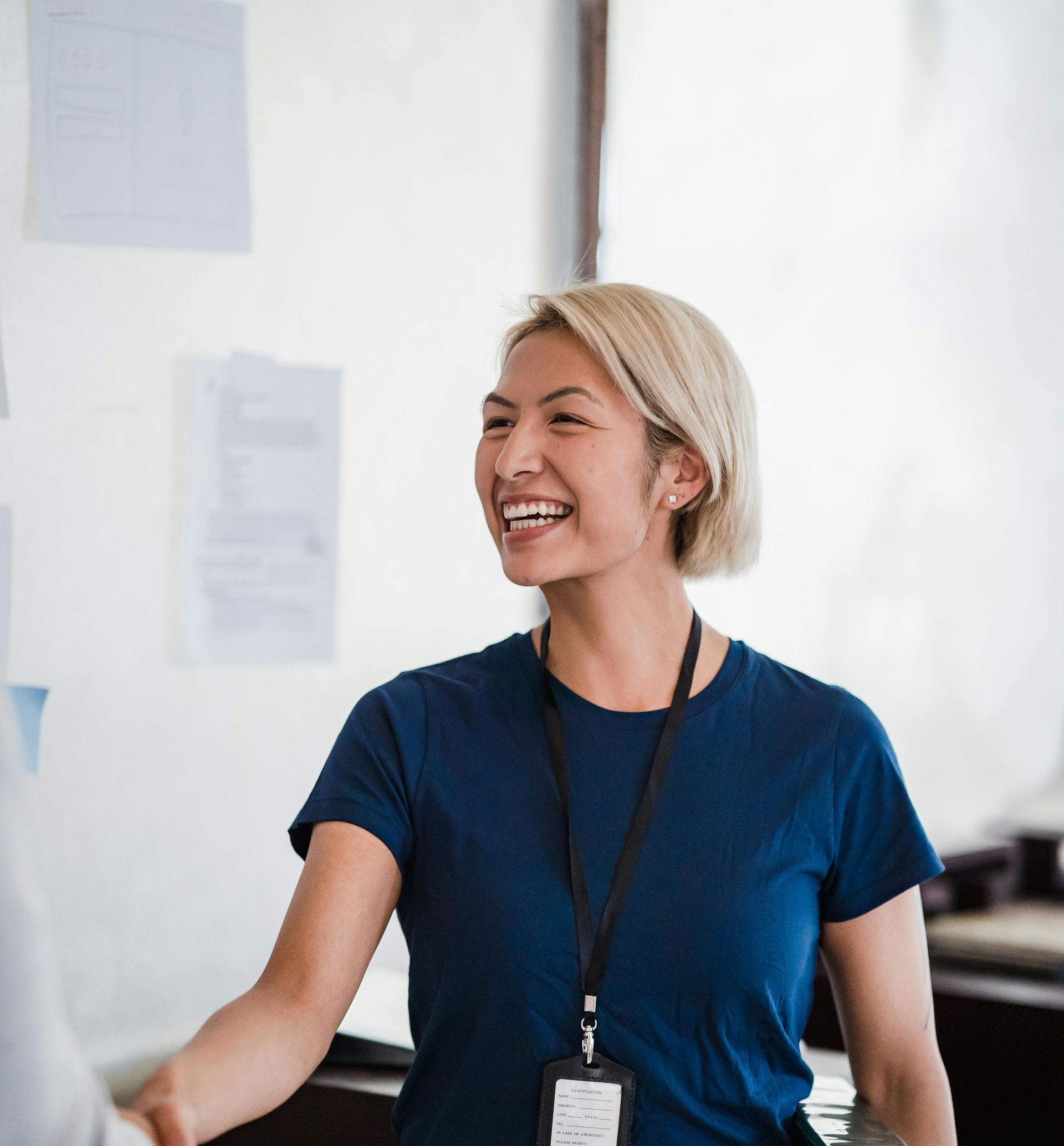 Smiling person in a blue shirt shaking hands in a bright office setting