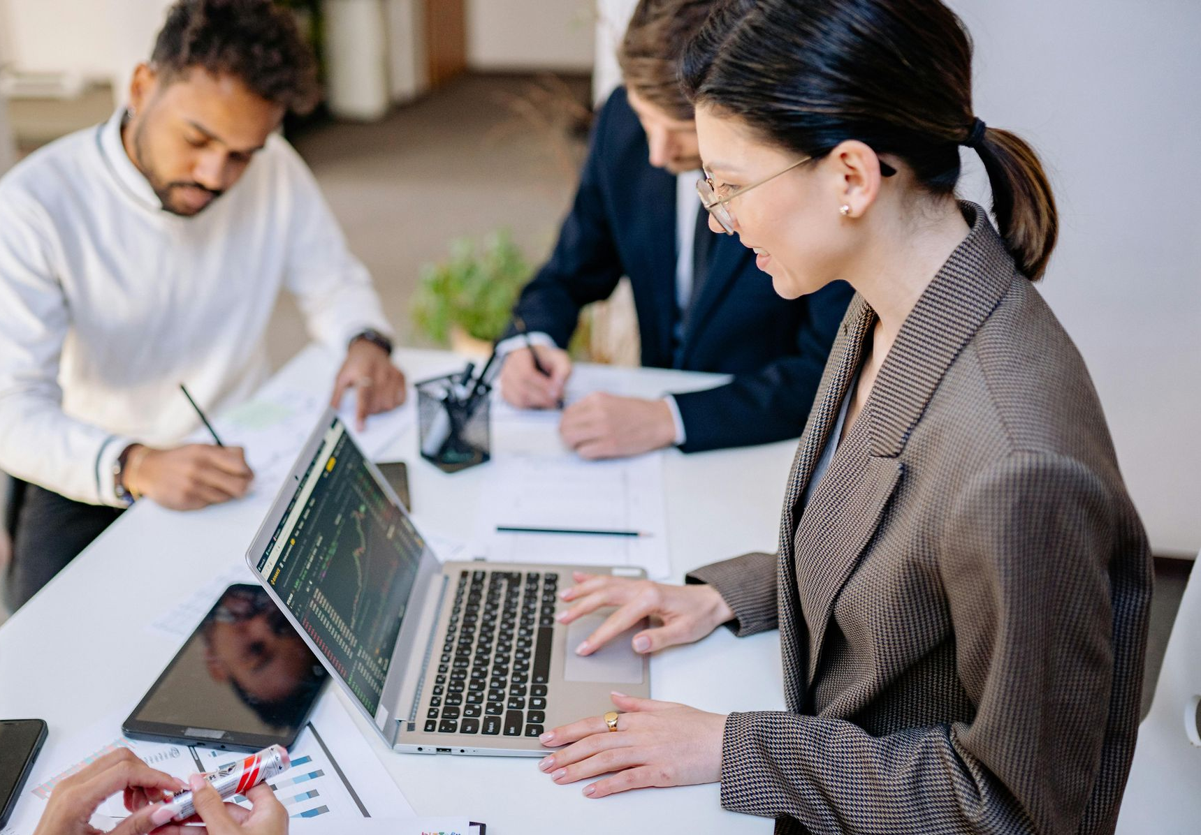 Team meeting around a laptop with charts and notes on a table