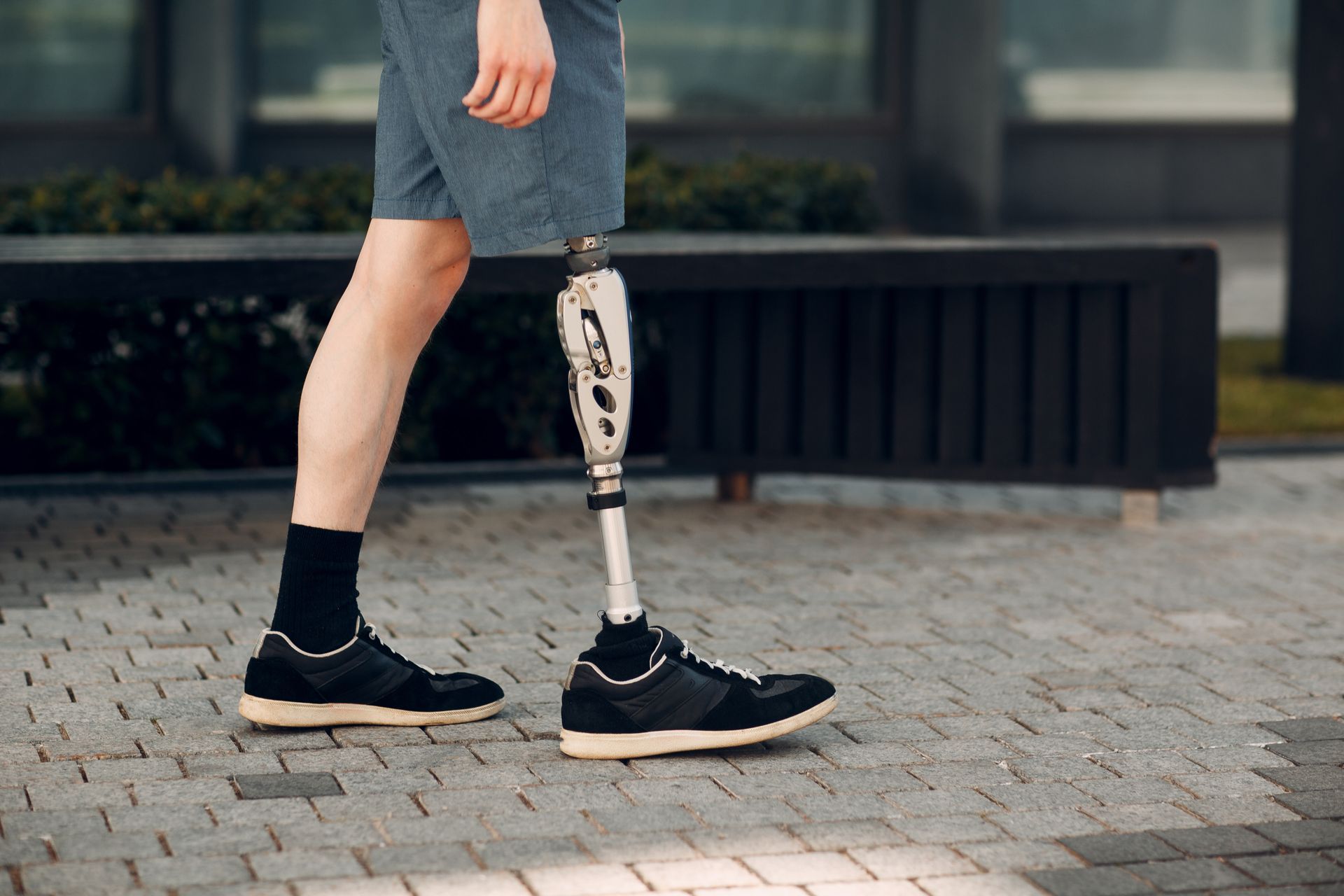 Man with prosthetic leg walking down a street.