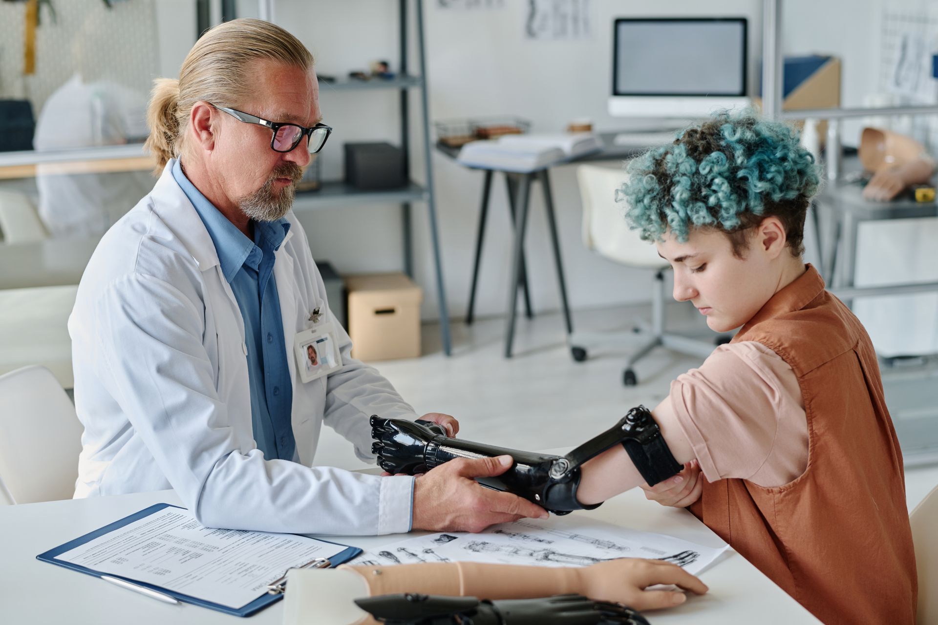 Prosthetics specialist assisting a young woman with her prosthetic arm.